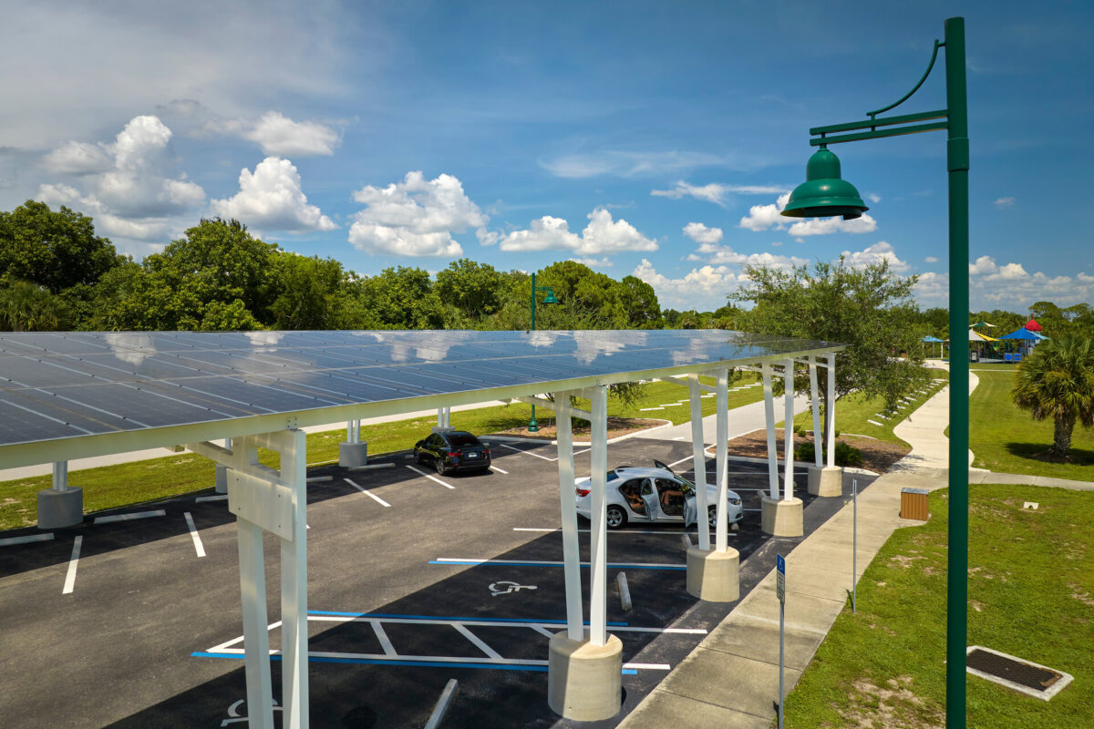Über dem Parkplatz für geparkte Autos installierte Sonnenkollektoren zur effektiven Erzeugung sauberer Energie. Carport mit Solardach.